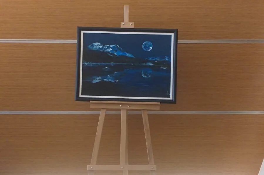 The same oil painting standing on a wooden easel.