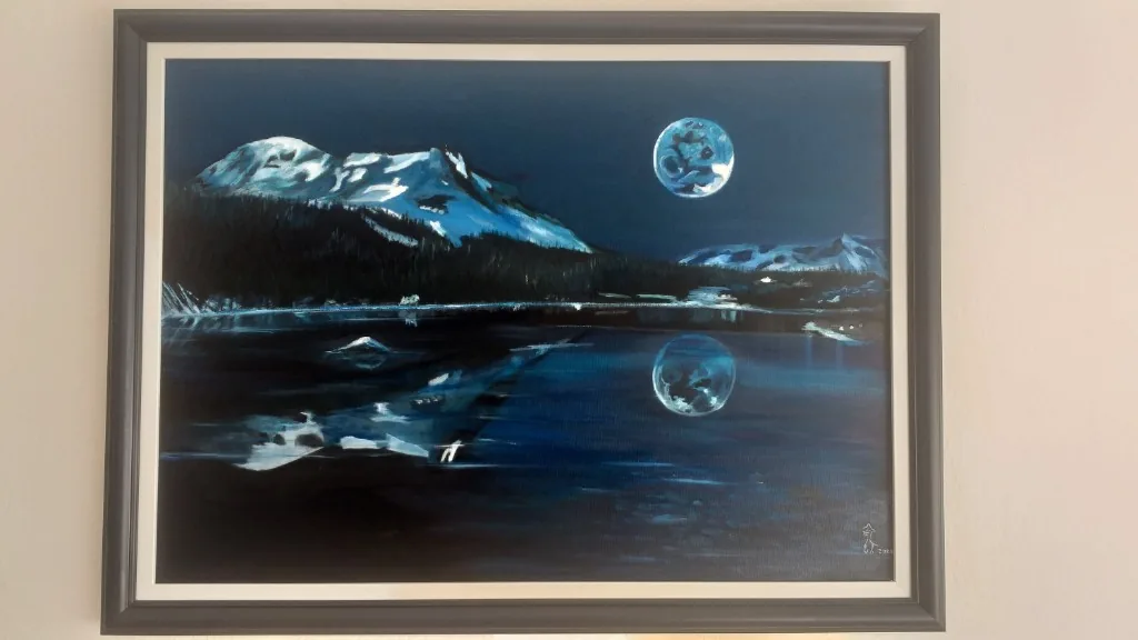 Framed oil painting of a moon over snow-lit mountains and their reflection in dark water.